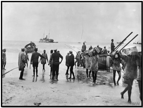أنفار الفرقة المصرية يقومون بإفراغ إمدادات على شاطئ غزة. ويظهر في الصورة ضباط إنجليز يشرفون على العمل والسياط في أيديهم